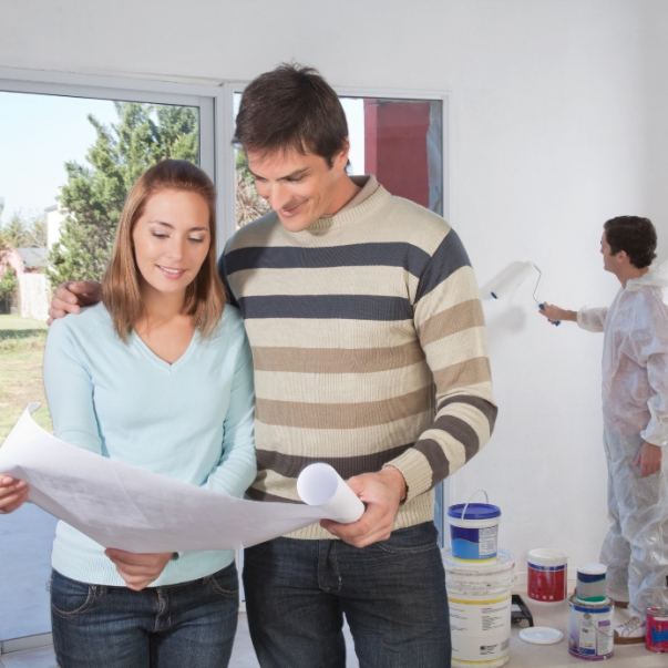 Couple going through house plan while painter in the background